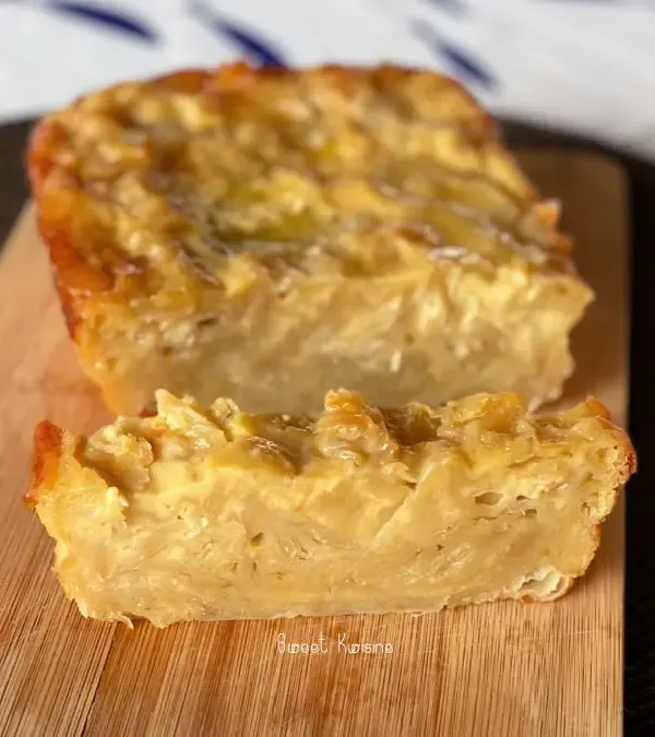 Une main soulève une feuille de pâte filo dorée, empilement de feuilles translucides sur un plan de travail en bois, torchon